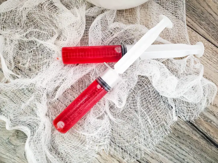 red jello syringe shots on white netting and grey background